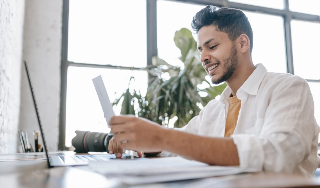 Young male photographer inputting information on his laptop