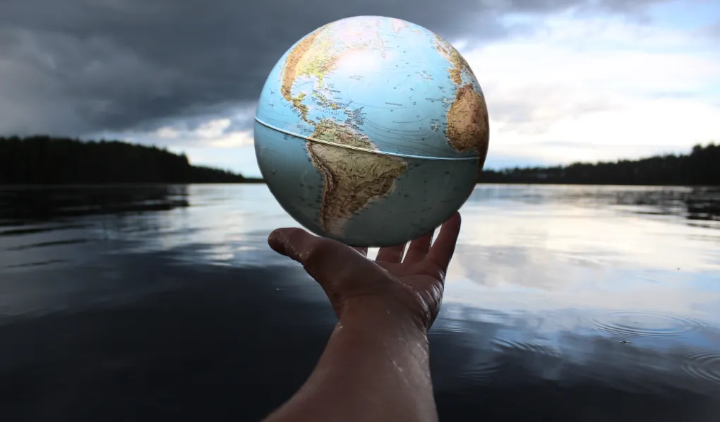Hand holding globe over a river