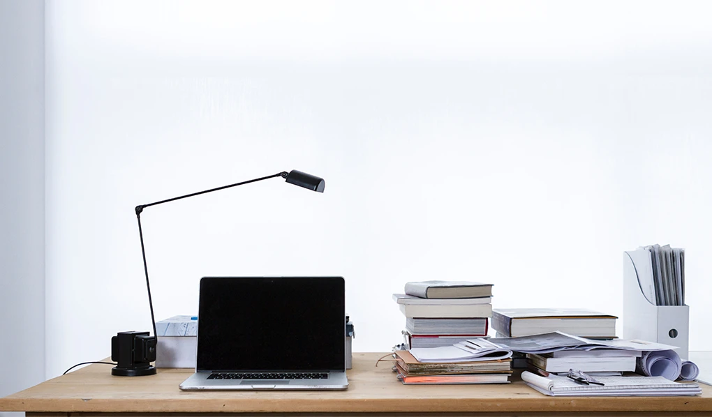 Work desk with laptop lamp and books