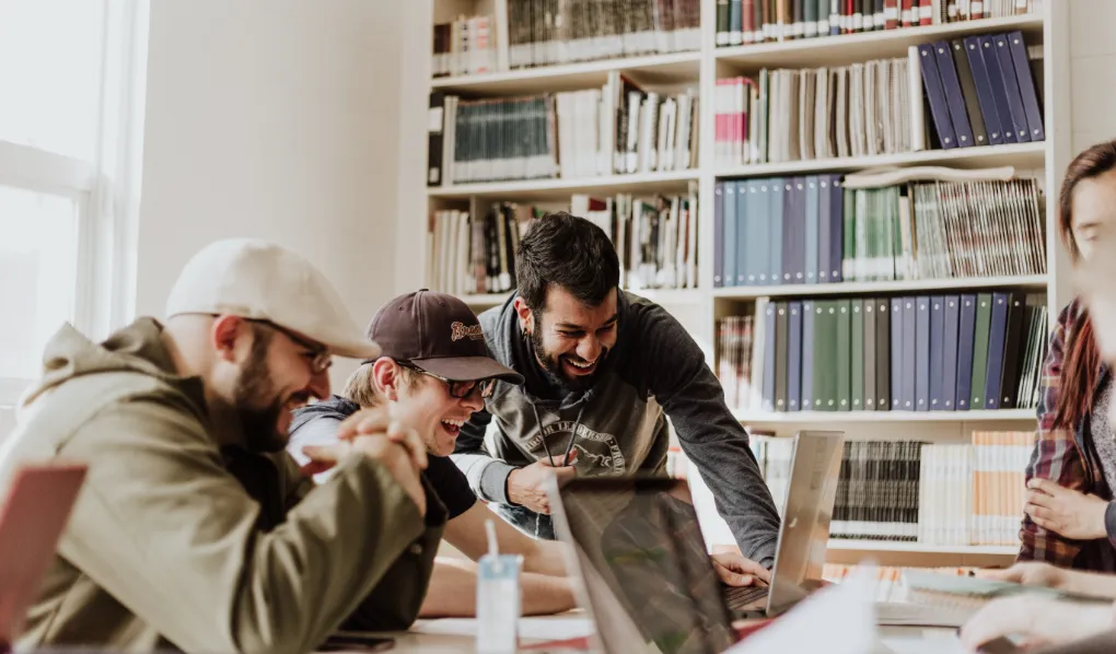 Bachelor of Communication students looking at laptop and laughing together