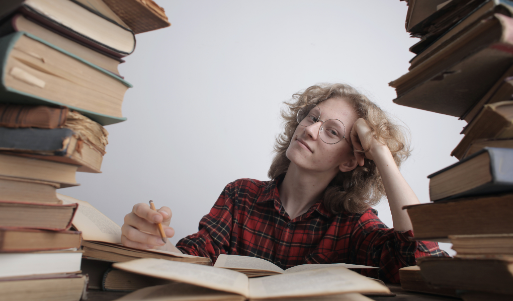 Student sitting in between books looking exhausted