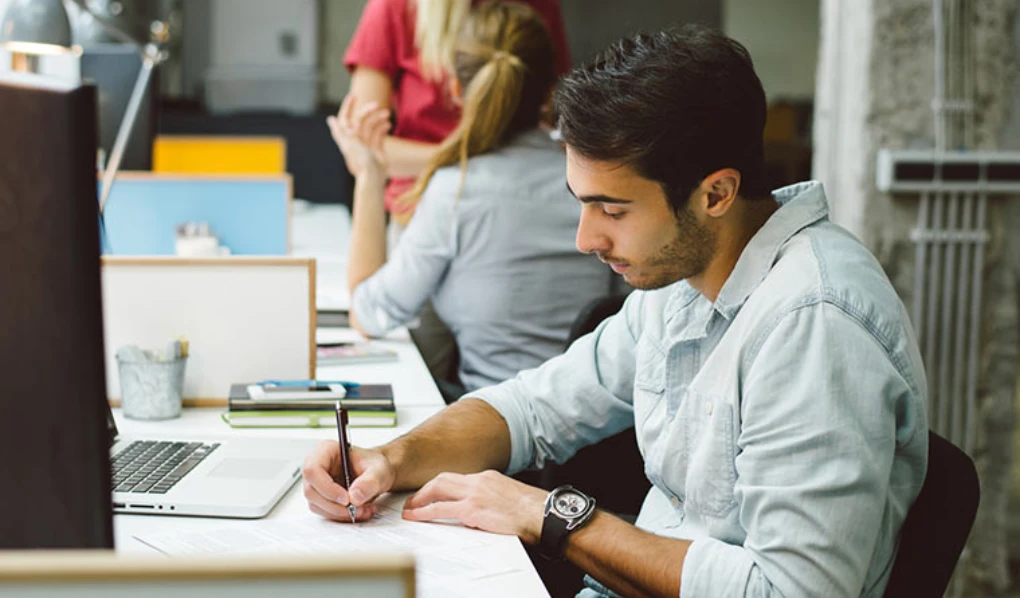Young male student making notes
