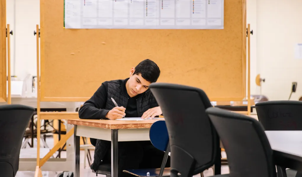 Male sitting down and writing notes at a career expo