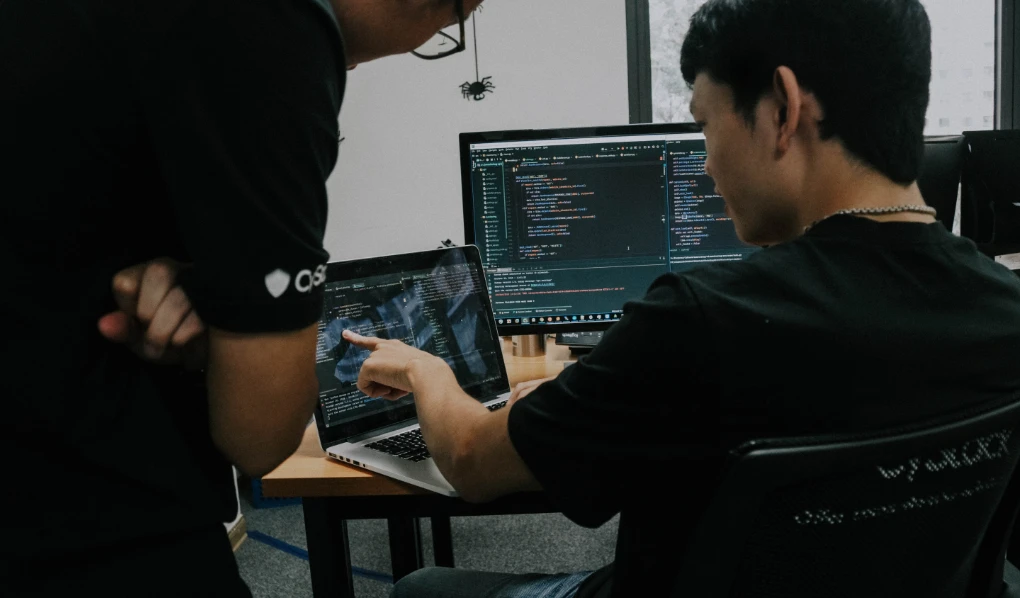 Cybersecurity professionals looking at screen with code on it