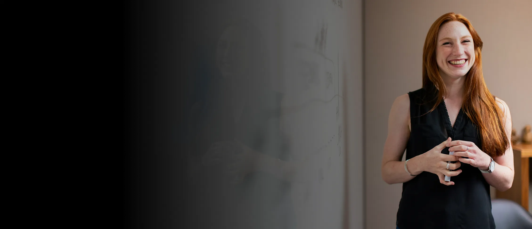 Red-headed woman infront of a whiteboard