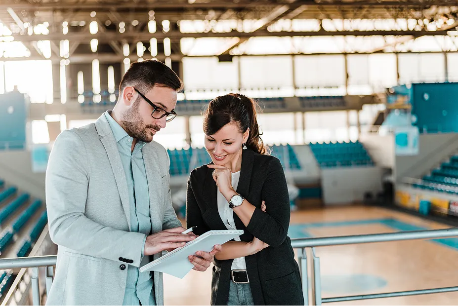 Man showing a woman paperwork while in a sports centre