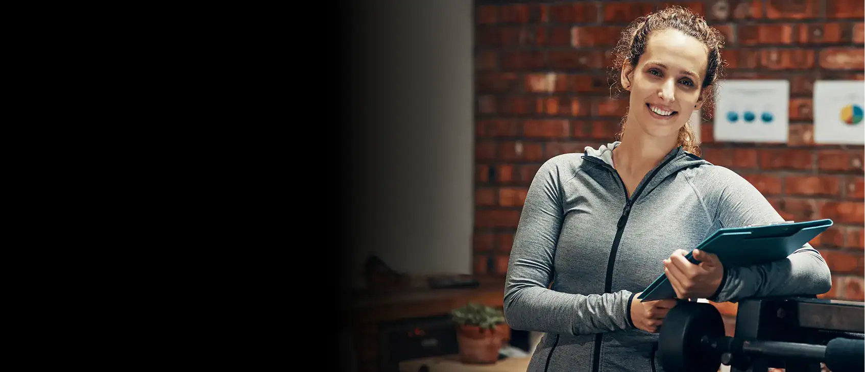 Young curly-haired woman smiling while standing with a clipboard