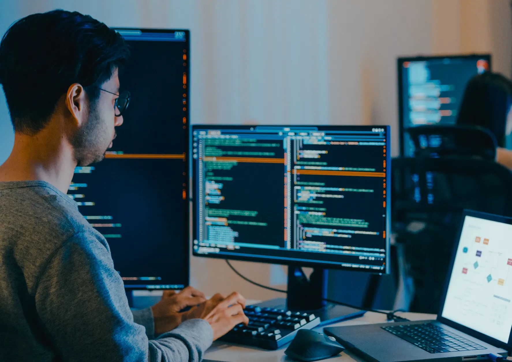 Young IT professional working on code on multiple screens