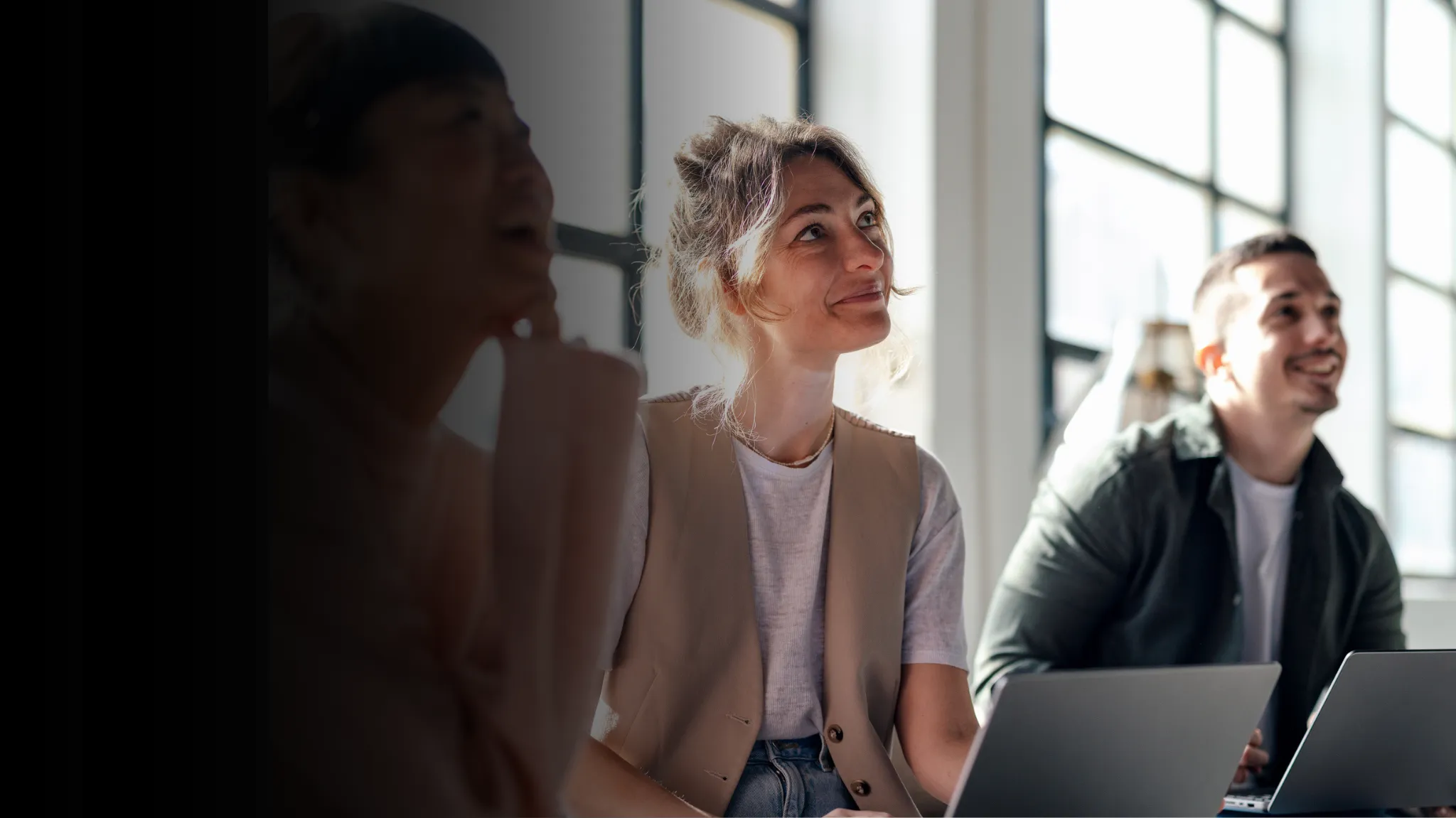 Two female and one male students smiling at something offscreen