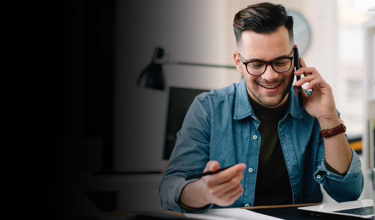 Young man with glasses smiling during a call on his mobile phone