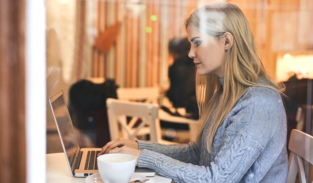 Young woman typing on a laptop in a coffee shop