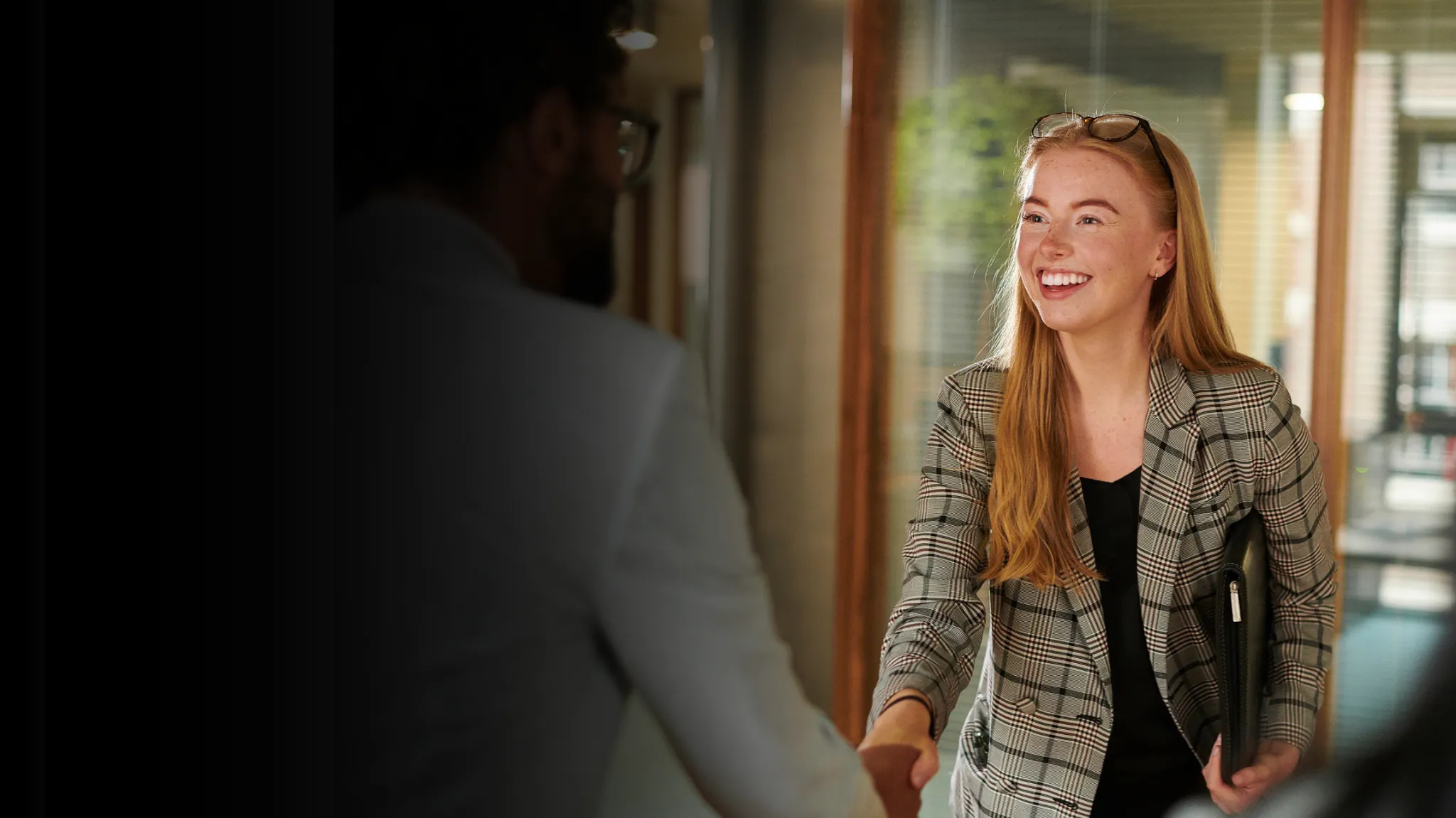 Red-headed young woman shaking hands with a man with glasses