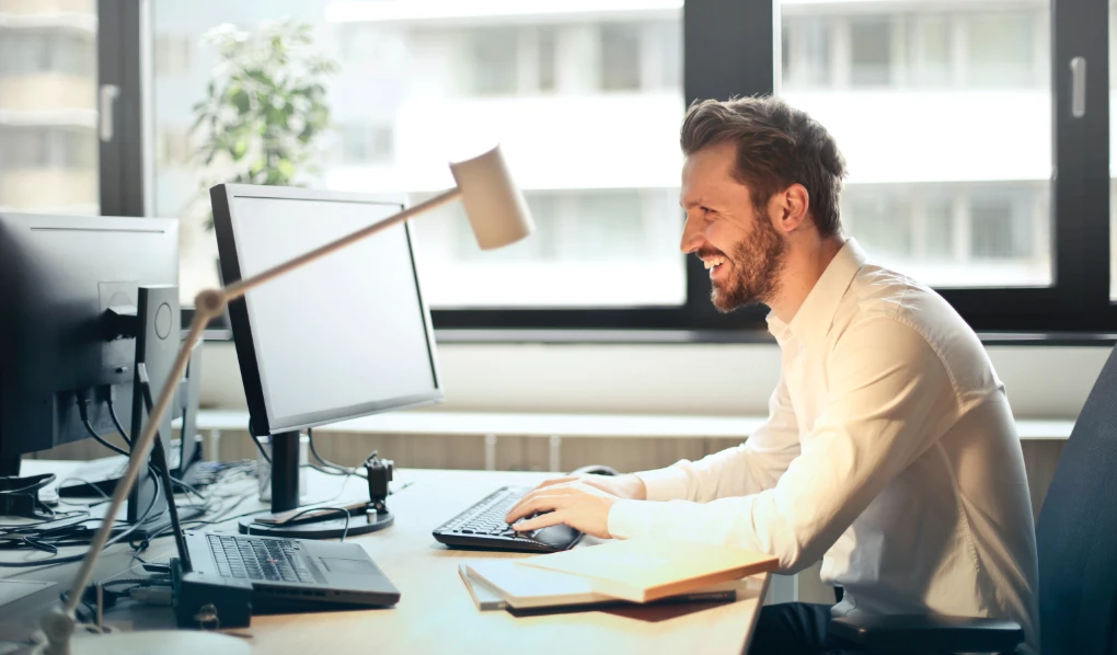 Happy young man smiling while working on laptop