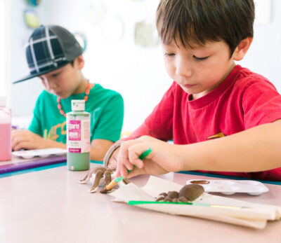Young children painting toys in class