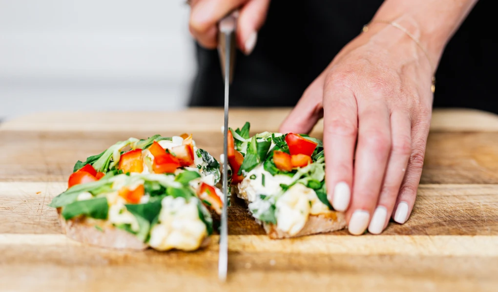 Hands cutting an open sandwich