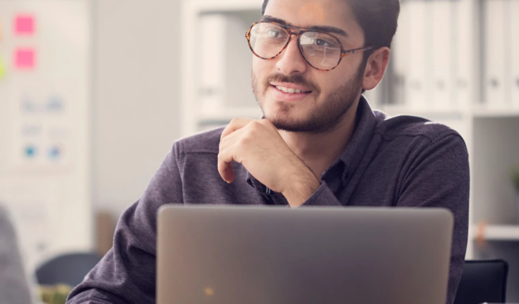 Young man with glasses working on laptop
