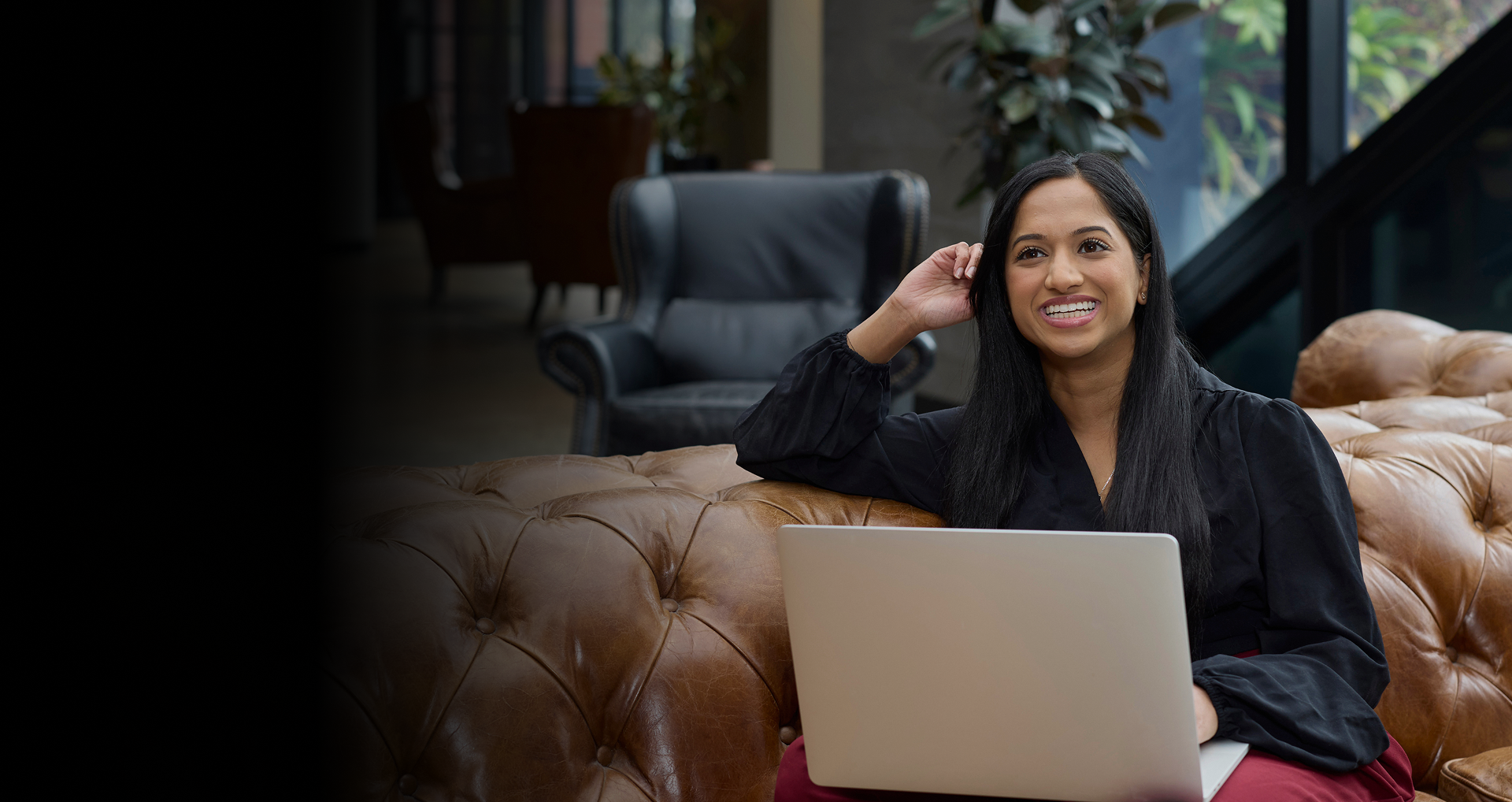 Young woman on couch studying and smiling.
