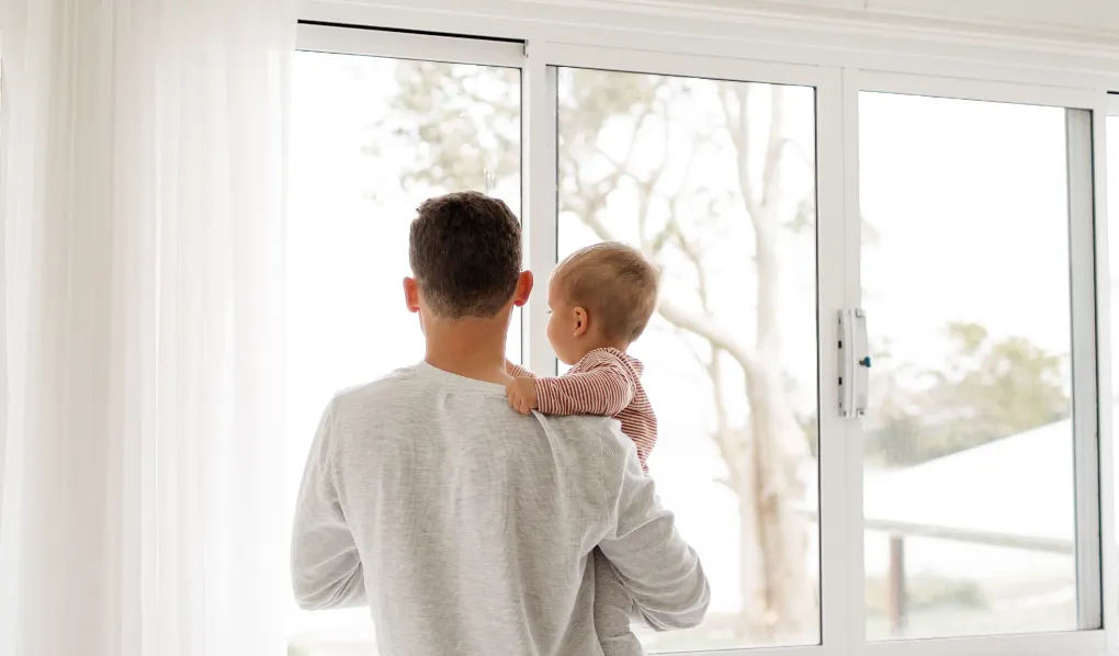 Father with baby looking out of a window