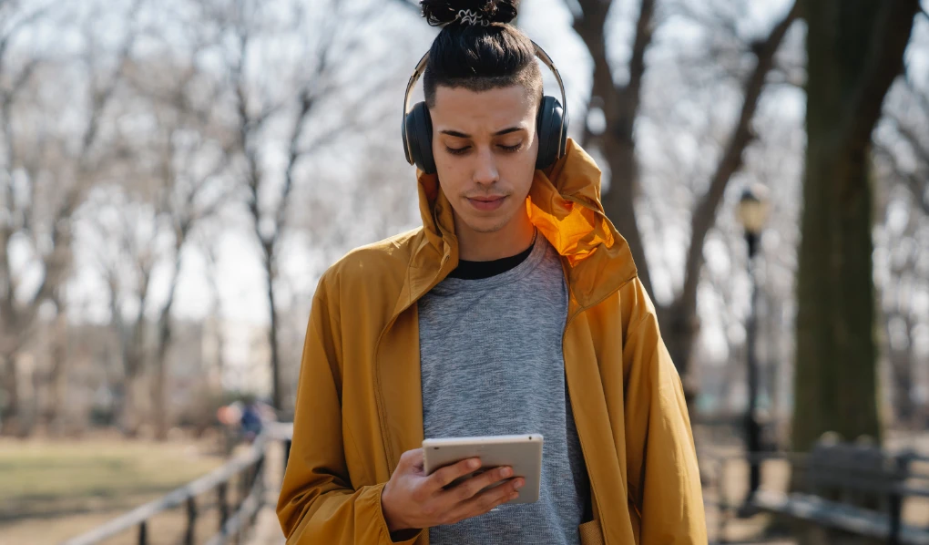 Male student listening to podcast on iPad