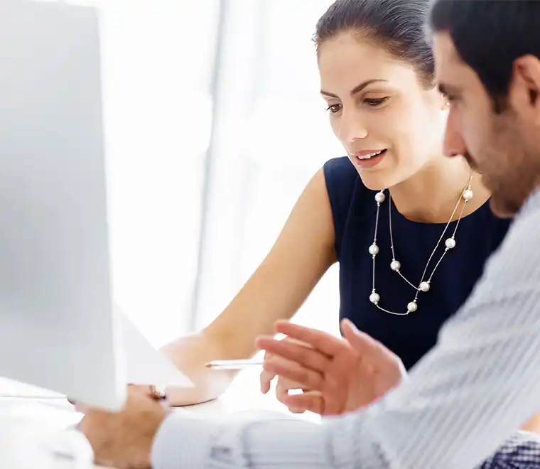 Two-colleagues-work-on-collaborative-project-using-laptop-and-referring-to-notes