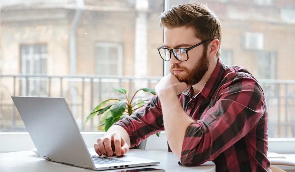 Young man working on his laptop at table