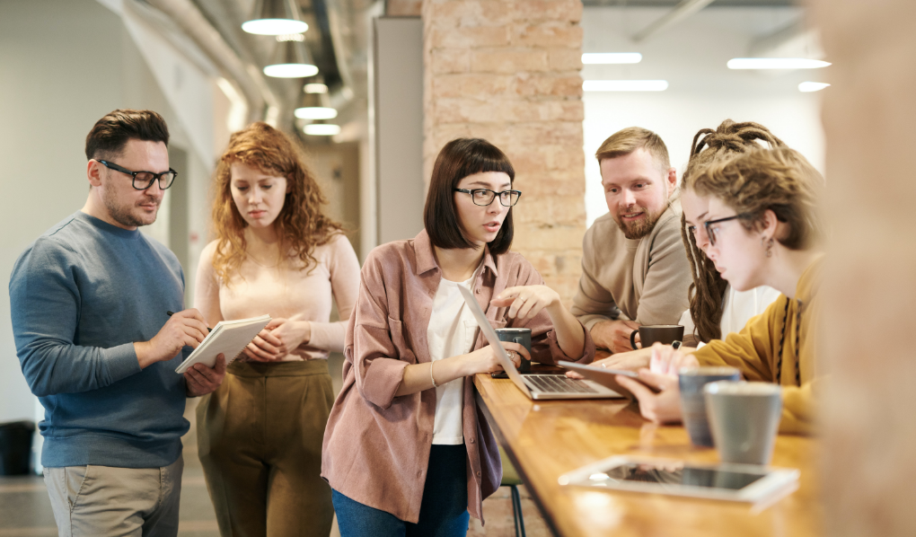 Hallway meeting of six colleagues with tablets and laptops