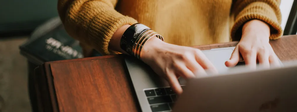 Hands typing on a laptop