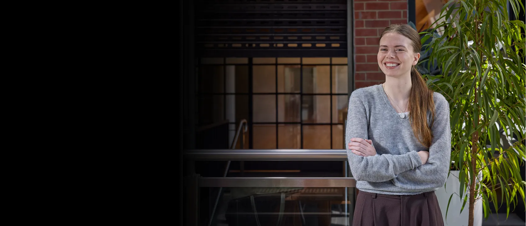 Young woman in a grey jersey standing with her arms crossed