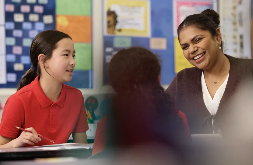 What skills do primary teachers need for today’s diverse classrooms - a teacher conversing with two students in a primary classroom environment